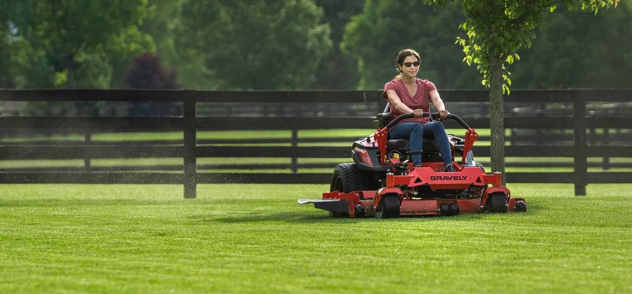Landscaping professional mowing a well-kept lawn with a riding mower.