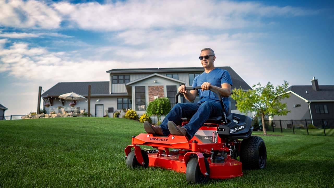 Professional gardener mowing the grass with a riding mower in a residential backyard.